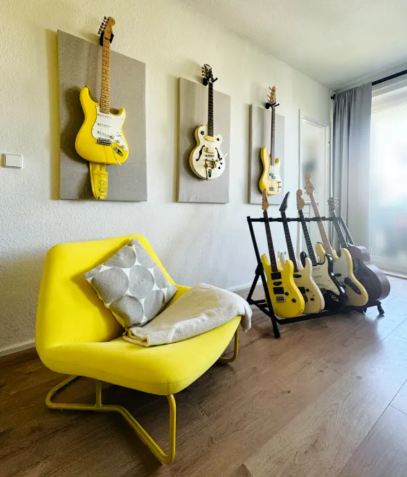 Bright studio with a yellow desk, monitors and yellow guitars on the wall